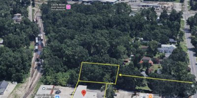 Aerial view of a commercial area with a large warehouse, parking, and nearby stores (Savannah Toolhouse, Jiffy Lube) with yellow parcel outlines.