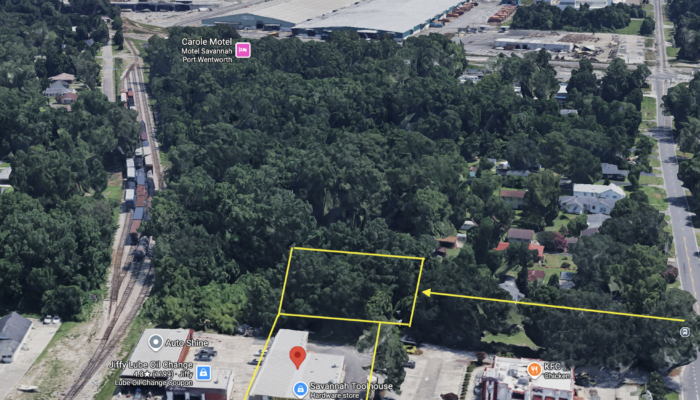 Aerial view of a commercial area with a large warehouse, parking, and nearby stores (Savannah Toolhouse, Jiffy Lube) with yellow parcel outlines.